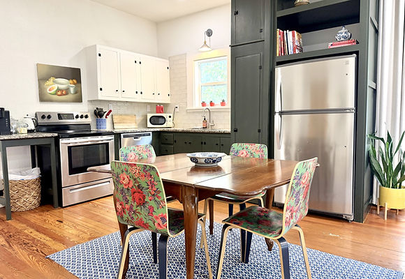 Kitchen and dining area at Barnett Bungalow with green cabinetry and floral dining chairs