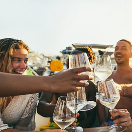 Multiracial people having fun cheering with wine at boat party outdoor - Focus on right gl