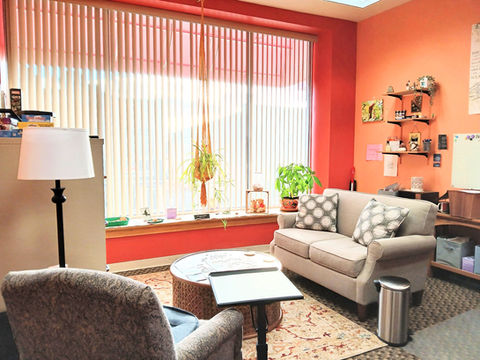 Peach Blossom Therapy office seating area with window and hanging plant in the background.
