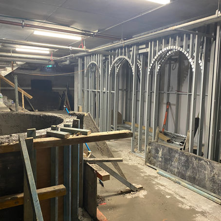 The concrete shell of the cold plunge and the steel-framed sauna arches at Navia Bathhouse.