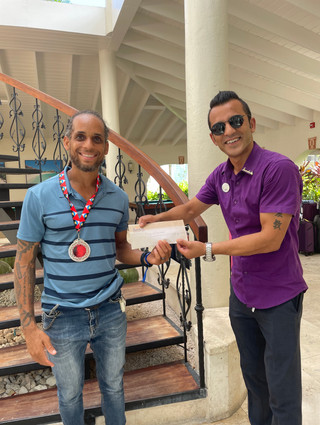 A man receiving a gift certificate from the Sandals Foundation.