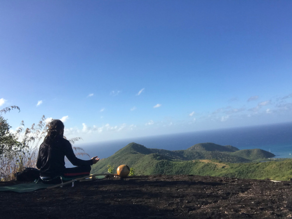Man sitting on yoga mat at the top of Antigua's Signal Hill