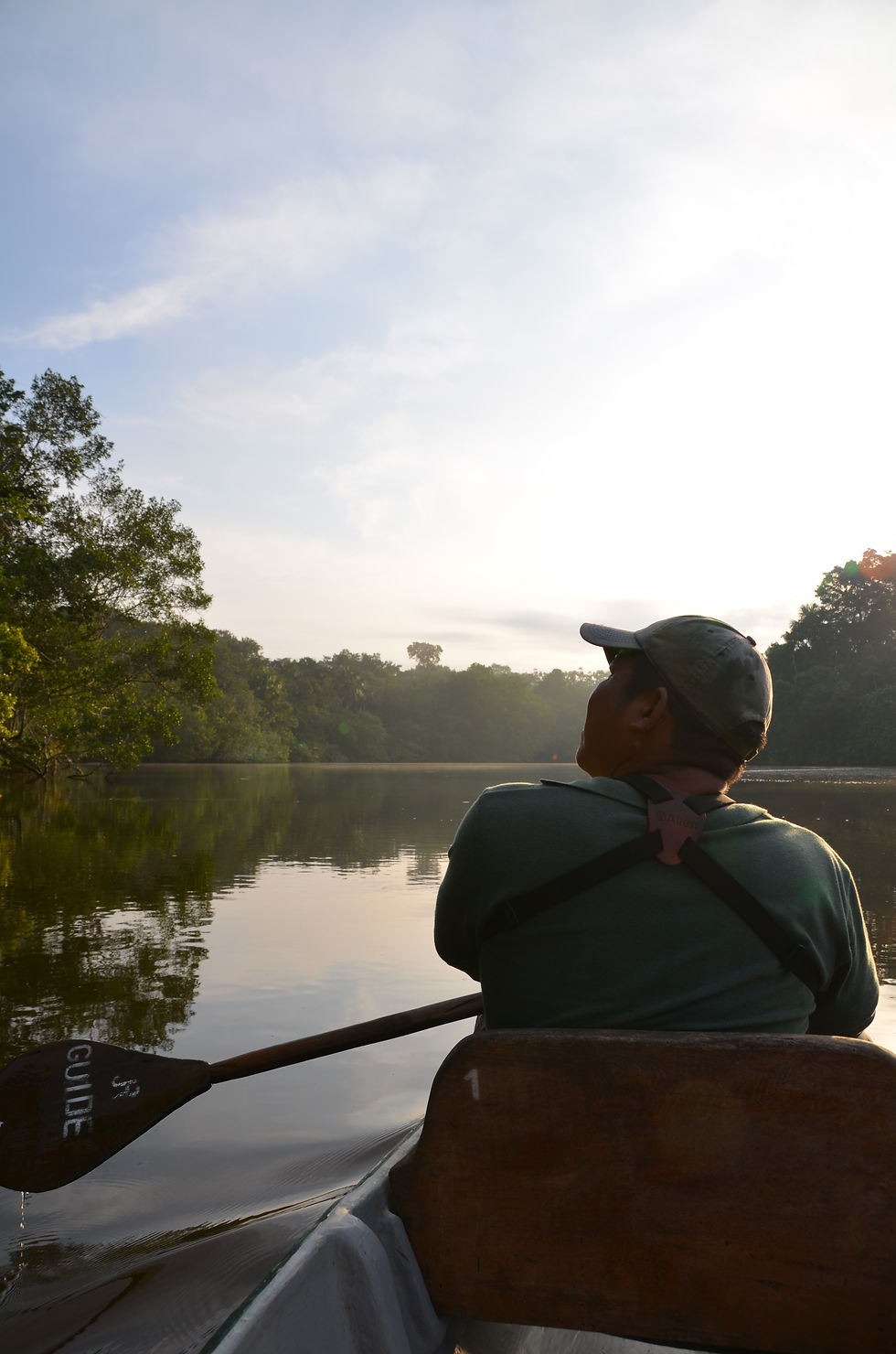 Amazon tour guide in a canoe holding a paddle on black lagoon