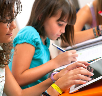 Two studets studying. One student is using a tablet and the other is writing on a notepad