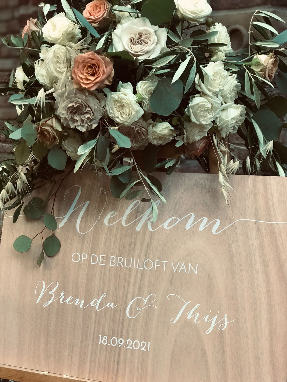 Houten welkomstbord met gepersonaliseerde opdruk met groot boeket