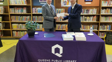 두 남자가 Queens Public Library에서 서류를 교환하고 있습니다. We speak your language.