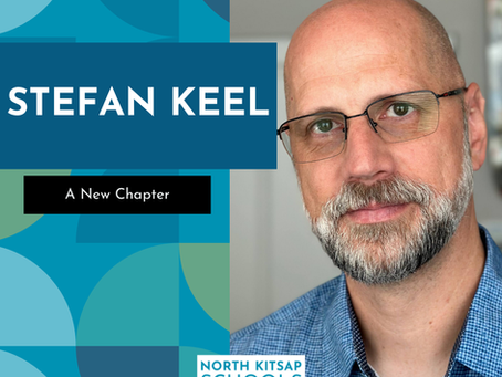 Stefan Keel wearing glasses and a blue shirt, smiling slightly, against a geometric teal background. Text: "STEFAN KEEL," "A New Chapter," "North Kitsap Schools Foundation."