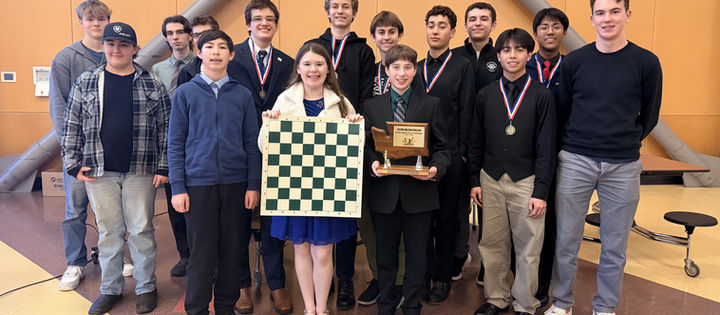 Group of smiling teens with medals; one holds a chessboard, another a trophy.