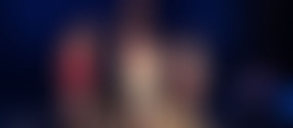 Theater scene with three actors in various poses on black steps. Multiple actors in background. Plastics scene in Mean Girls.