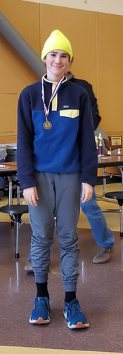 A student with a neon beanie smiling with a medal.