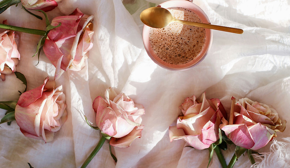 A-pink-cup-of-cocoa-with-a-golden-spoon-surrounded-by-pink-roses-on-white-fabric-feminine-
