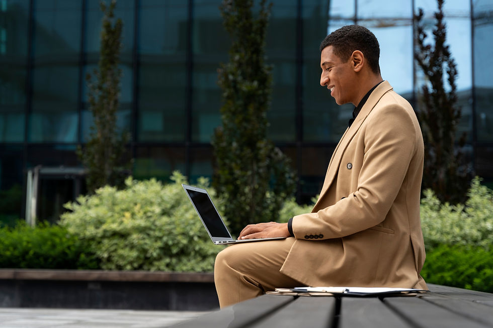 Happy man in suit using laptop outdoors, working and smiling.