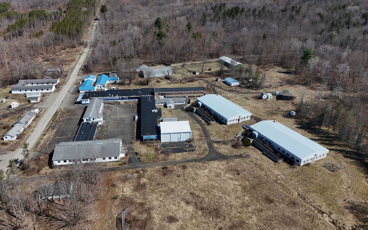 Rows of single-story buildings with blue and gray roofs along the camp roads