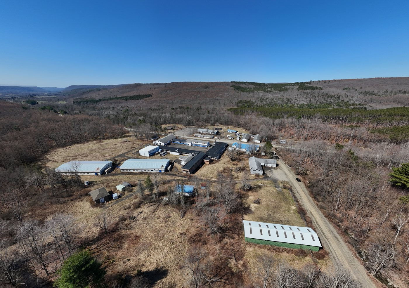 Drone photograph of the former Camp Monterey buildings in a wooded valley under a blue sky