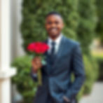 a young black man dressed in a very nice suit for a formal occasion like a prom or a very
