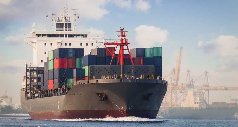 Aerial view of a massive cargo ship navigating through a bustling port with cranes unloading containers.