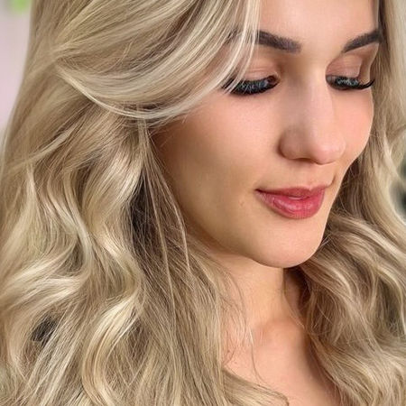 Mulher com cabelos loiro vanilla iluminados em ondas suaves. As mechas criam luminosidade natural e elegante. No Dona Bela Cabelo & Cia em Rio Claro, cada detalhe revela estilo e autoestima.