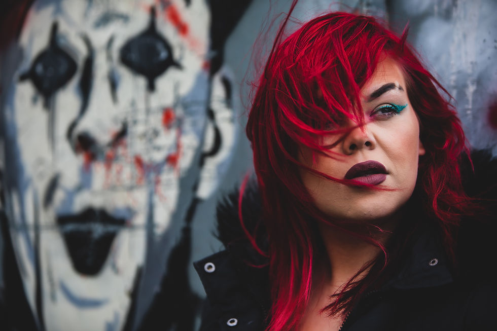 Creative portrait of a red-haired woman against expressive street art, photographed by Annie Rees during her Fine Art Photography studies.