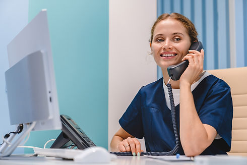 Smiling young woman nurse receptionist talking on phone while working in modern clinic. Ma