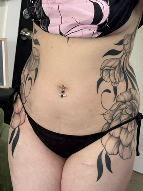 large, cohesive symmetrical black and grey ornamental tattoo on a woman's hips and ribs done tattoo artist by Matisse Maugh of Bloodstone Tattoo Studio in Tacoma, Washington.