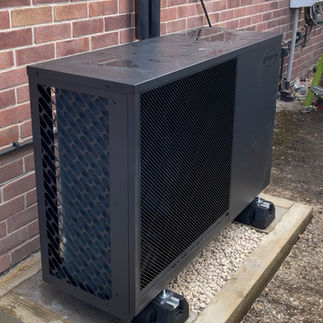 Grant Heat Pump in gravel base outside a side wall of a house