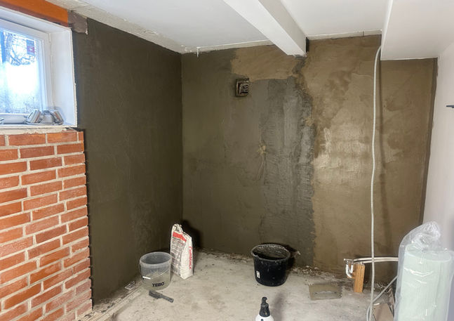 Renoverat rum med putsade väggar och byggmaterial på golvet.