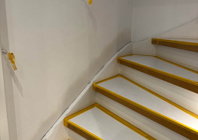 Vita trappsteg med gul tejp längs kanterna, redo för målning.