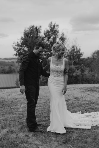 A candid black and white wedding portrait of a bride and groom sharing a genuine moment outdoors in Alberta. Captured in a cinematic western style, this image reflects authentic emotion, natural connection, and timeless storytelling. Perfect for couples looking for a wedding photographer in Alberta who focuses on real moments and intentional imagery.