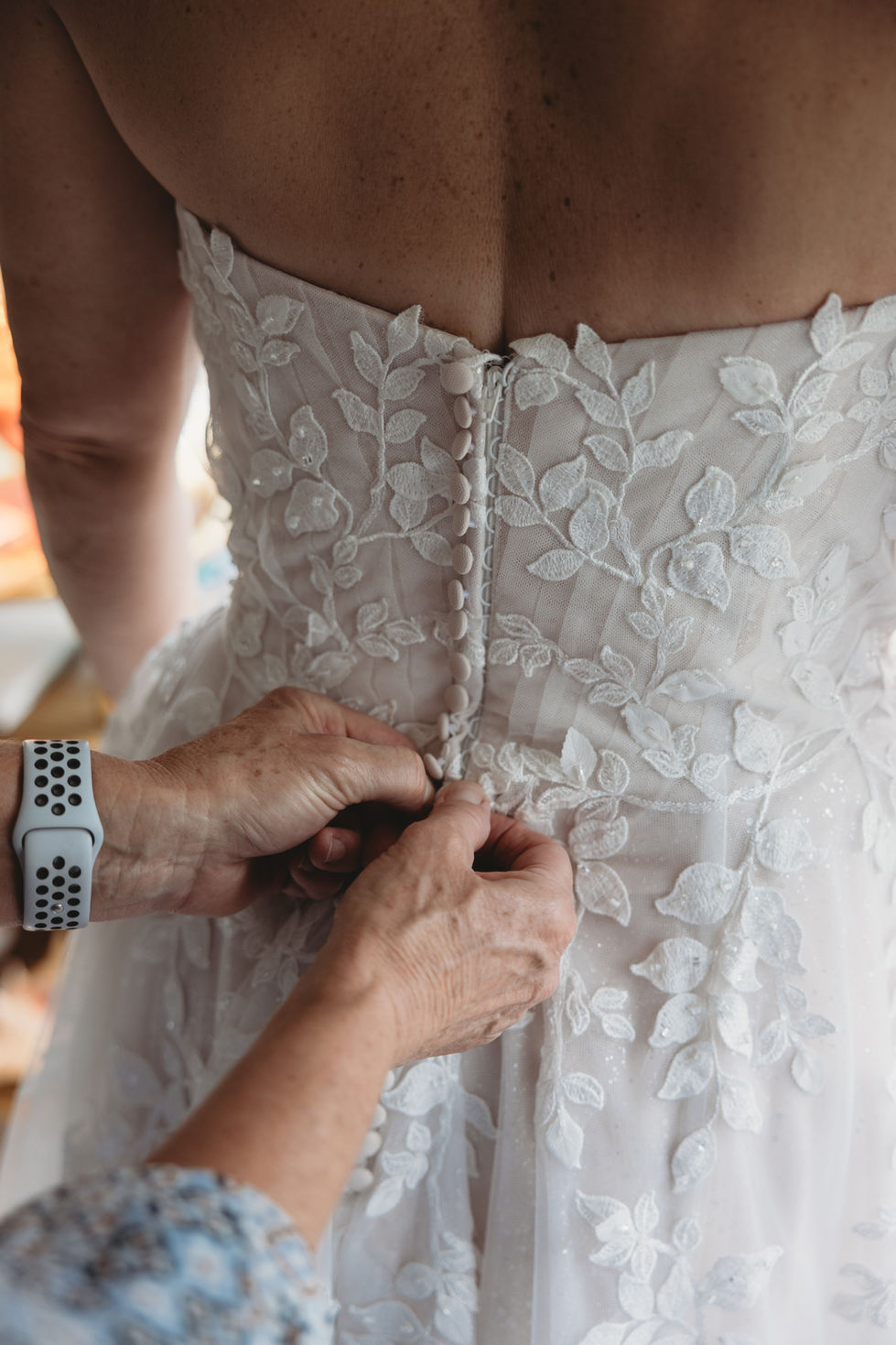 a woman wearing a nike watch is helping a bride with her wedding dress