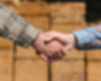 Handshake in front of stacks of hardwood lumber.