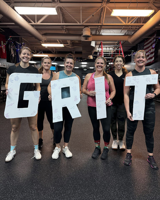GRIT Fitness members hold up a GRIT sign.