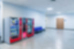 Group of red vending machines stands by the wall. Glare is reflected on a black screen. No