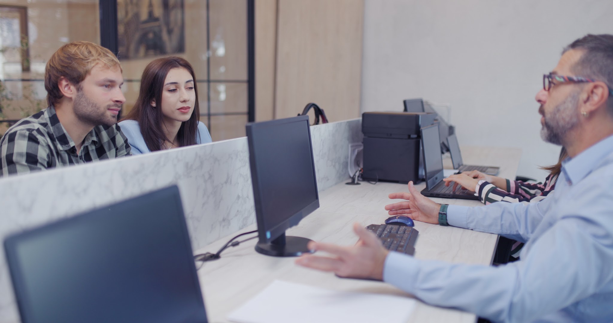 Couple consulting a travel agent and reviewing options on a computer