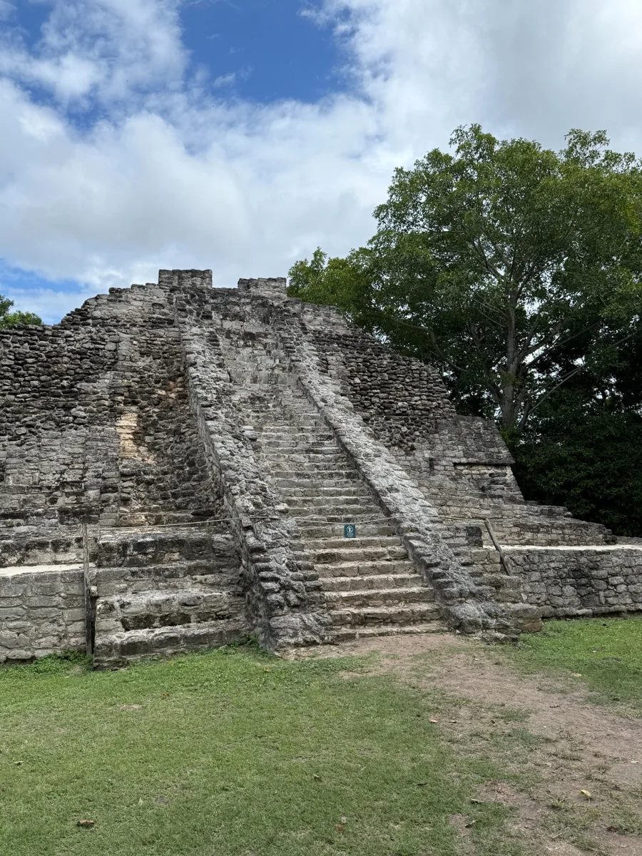 Stone temple and central staircase at Chacchoben beneath a blue sky