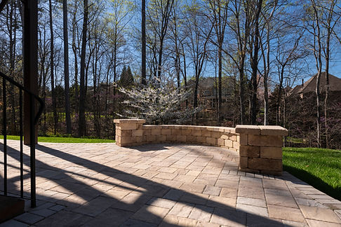 Picturesque backyard view in spring season with patio pavers and stone wall, blooming whit