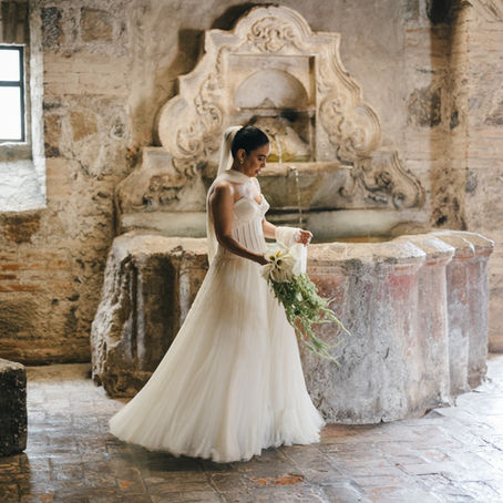 A bride at Casa Santo Domingo, Antigua Guatemala, on her lavish wedding day. In the background are a statue and a fountain.
