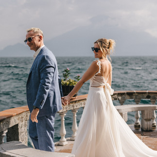 A bride and groom walking hand in hand on a balcony overlooking Lake Atitlán and a mountain. A luxury wedding at Casa del Mundo.
