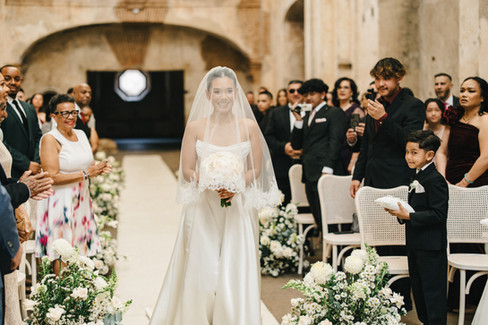 The bride walks down the aisle surrounded by friends and family at the Ruins of Santa Clara in Antigua Guatemala.
