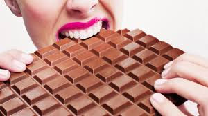A woman eating a hge chocolate bar