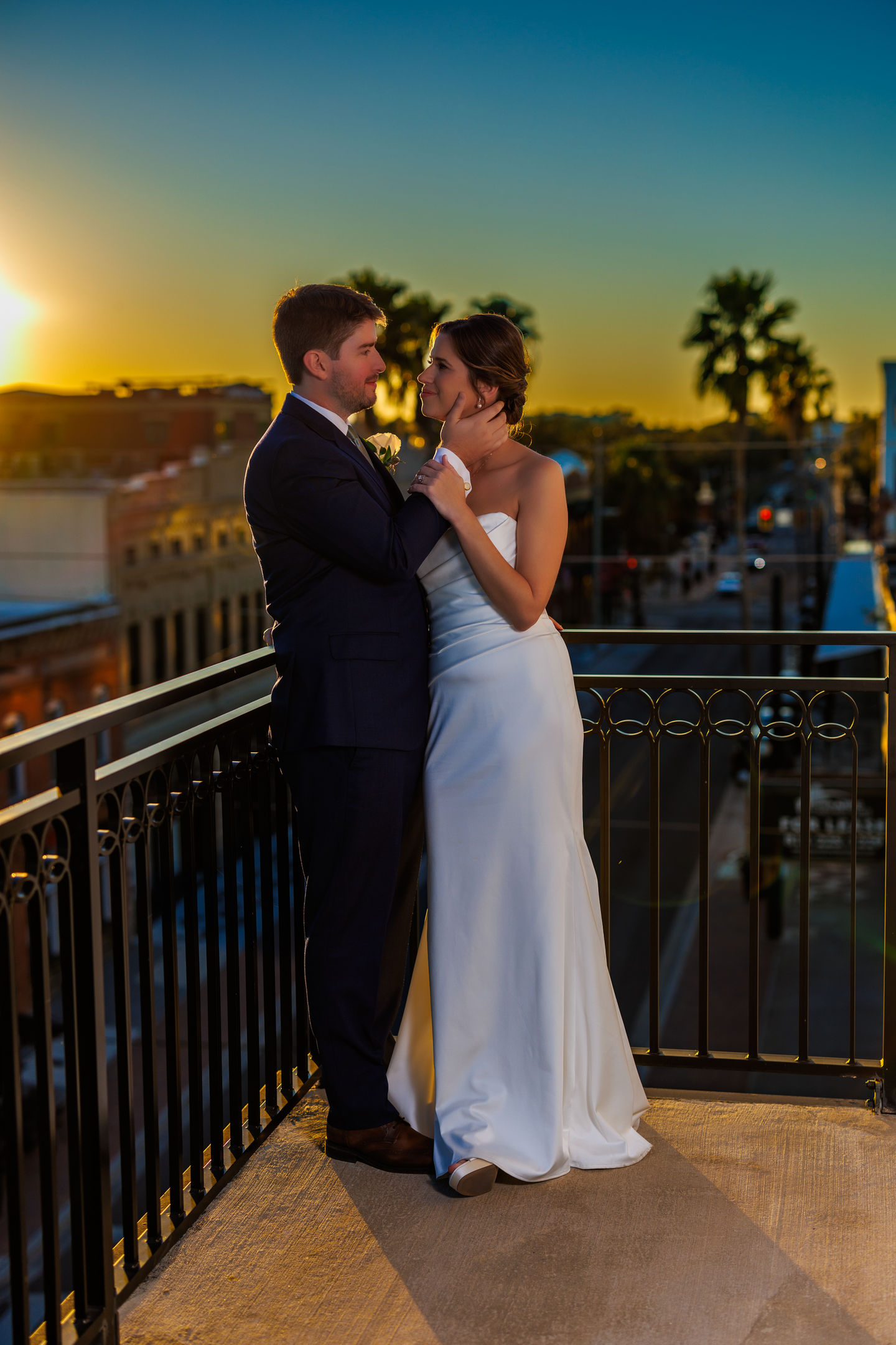 a bride and groom on a balcony at sunset