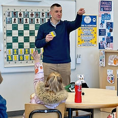 Chess coach teaching students with a demonstration board during an after-school lesson