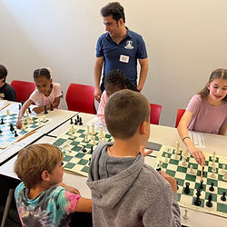 Chess coach providing instruction to elementary students during an after-school chess club