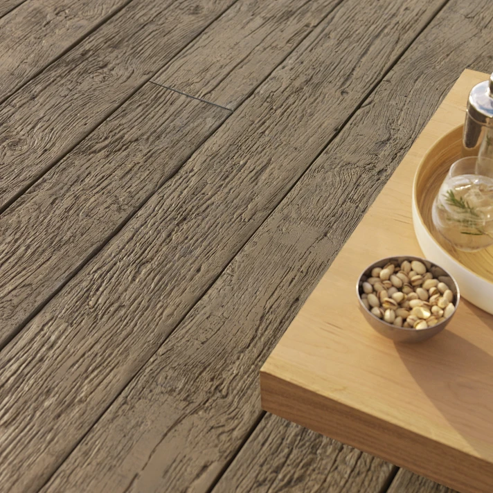 Zoom sur terrasse en bois vieilli avec planches texturées et table en bois clair avec plateau de collations.