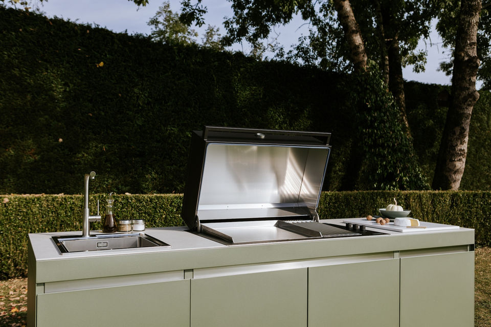 Cuisine extérieure modulable avec plancha couverte, évier intégré et espace de préparation, offrant une solution pratique et esthétique pour cuisiner en plein air.