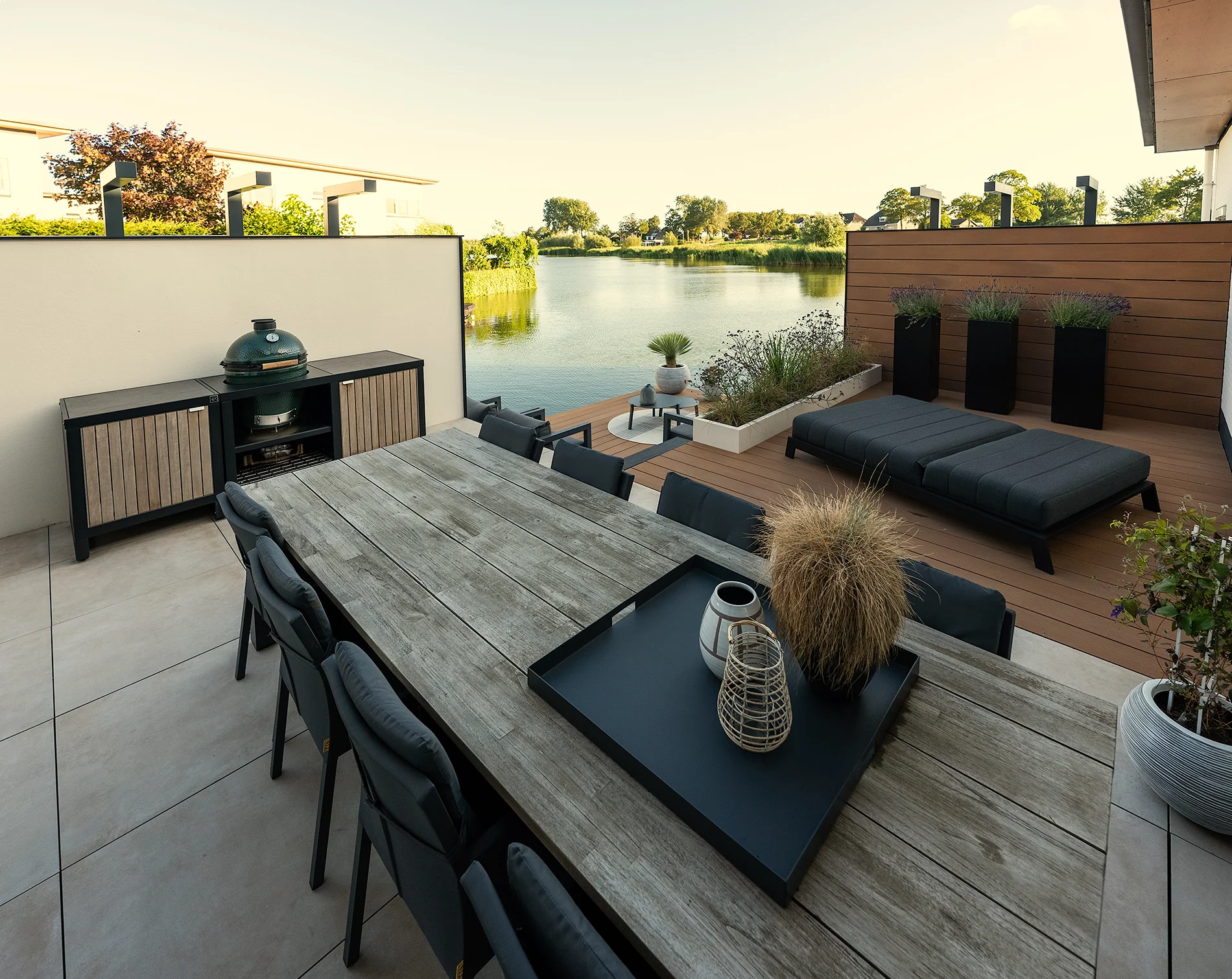 Cuisine Rubix au bord de l’eau : structure noire, portes bois clair et Kamado Big Green Egg encastré, ambiance lounge sur terrasse.