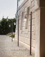 Alignement de mâts d’éclairage Aldo Bernardi en laiton bruni avec lanternes verre le long d’une façade classique.