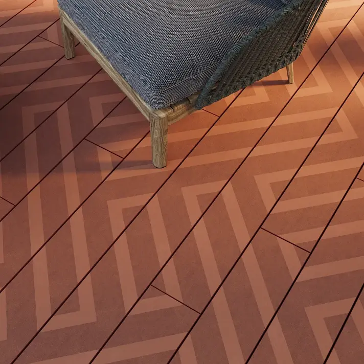 Lames de terrasse Millboard Linear à motifs géométriques façon chevron, en coloris Jarrah, avec fauteuil tressé posé sur la terrasse.