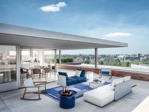 Tables basses BRISE en bleu et blanc sur un rooftop avec mobilier lounge et vue sur la ville.