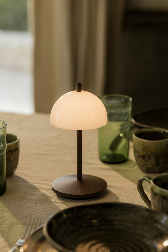 Lampe KOS QOOZII coloris Corten allumée sur une table dressée en intérieur