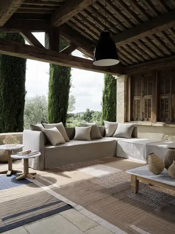 Canapé d'extérieur GHOST OUT de Gervasoni installé sous une terrasse couverte en pierre, ambiance naturelle et chaleureuse